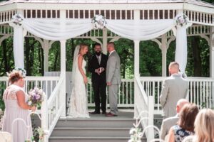 Bride and groom face each other with officiant behind them.
