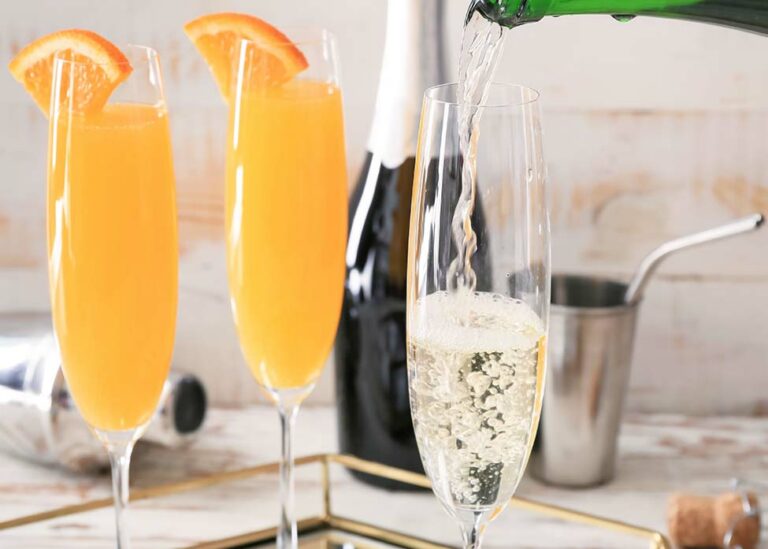 Two mimosas next to a glass of champagne being poured.