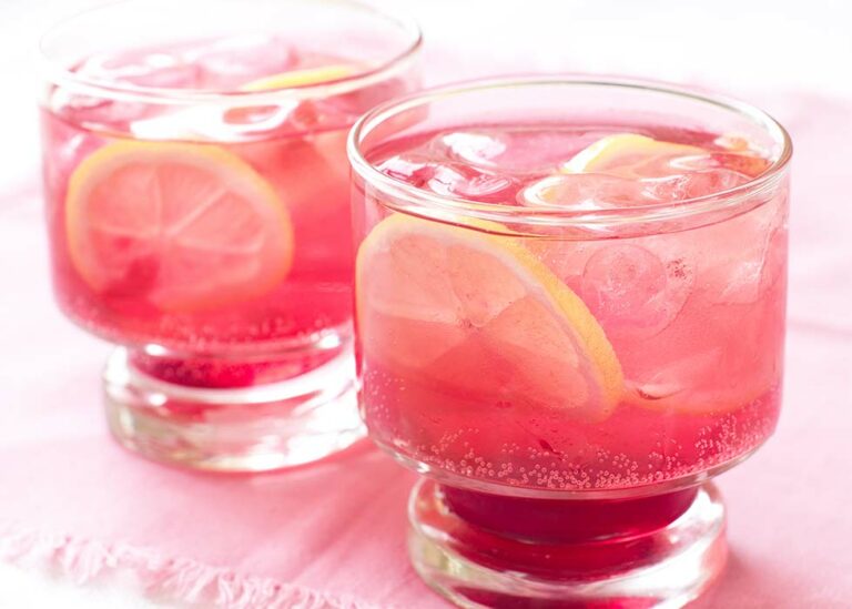 Two pink cocktails in short glasses with lemon garnish.
