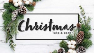 Photo of a Christmas wreath on a white wood background with the text "Christmas Take & Bake".