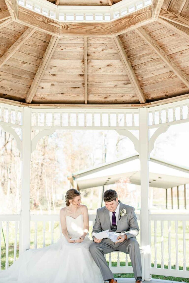 Newlywed couple sitting in the ceremony gazebo at A Touch of Class reading their vows to each other.